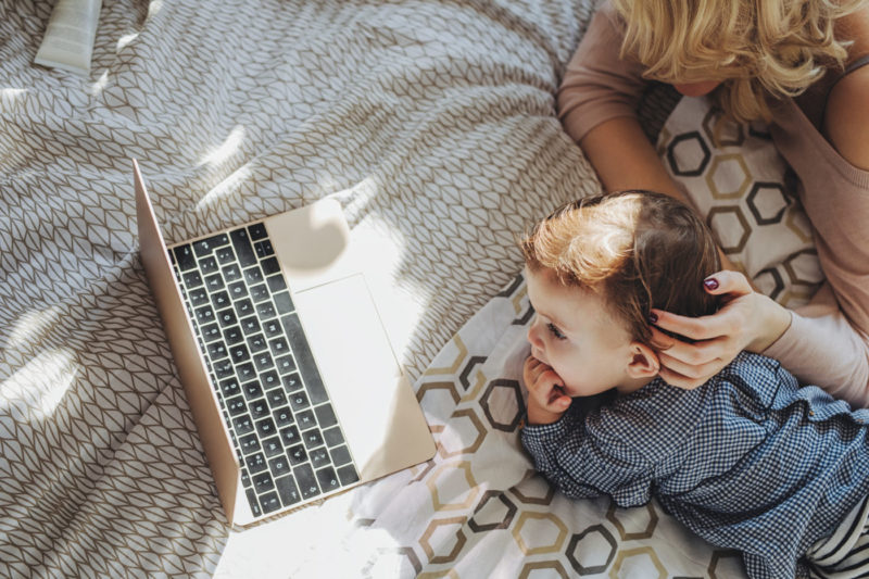 Mother and baby looking at a laptop checking reviews.